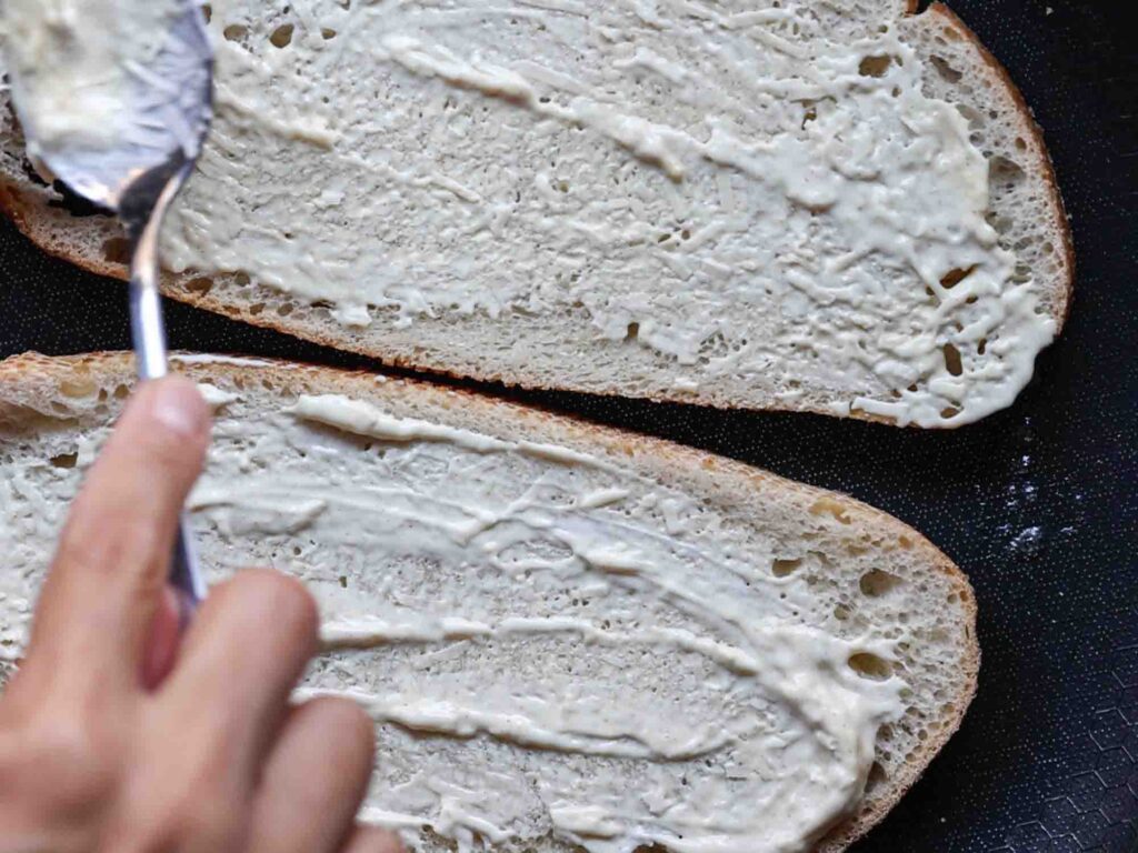 adding dressing to bread on pan